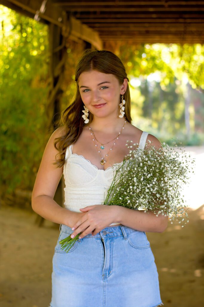Prospect Park Redlands CA, high school senior smiling at camera wearing jean skirt and white tank.