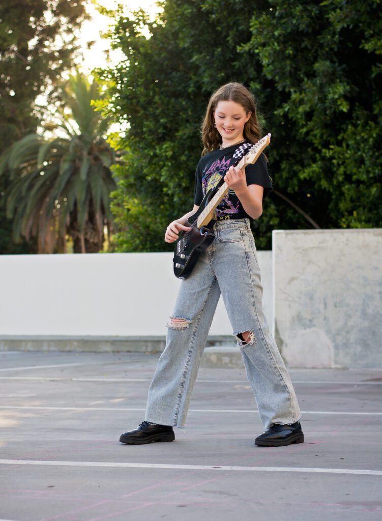 Tween photographer Riverside CA photographing tween girl with electric guitar in ripped jeans and rocker tee in Downtown Riverside